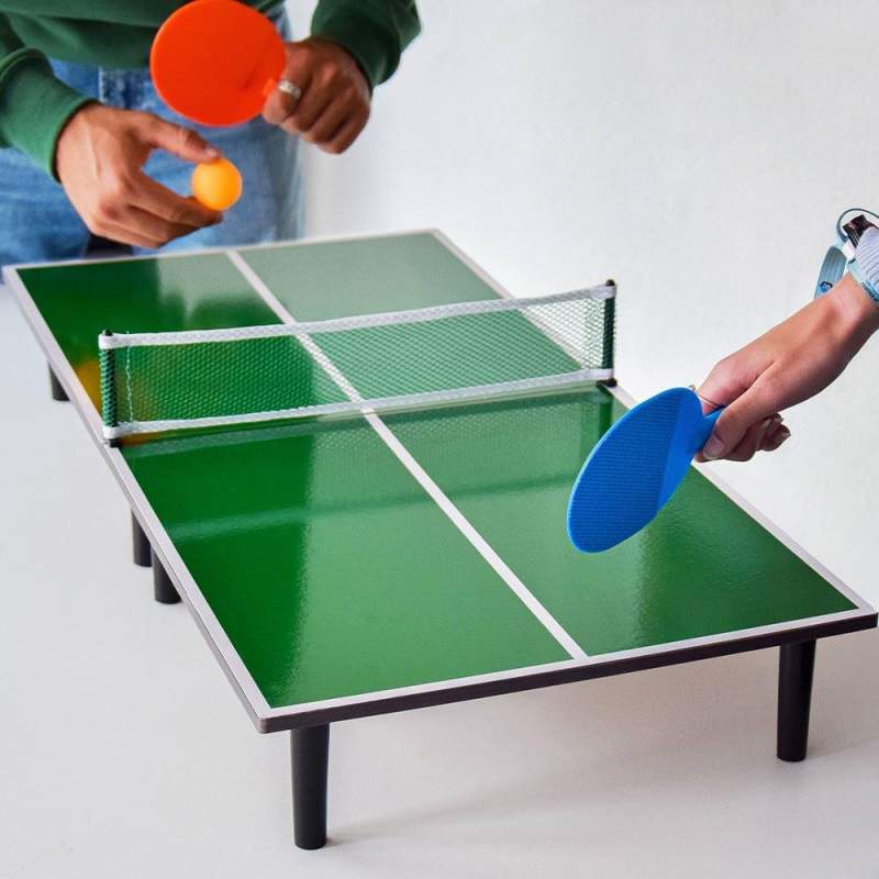 A picture containing two people's hands, each holding a table tennis paddle. The far one holds a ball, looking like he's preparing to serve it.