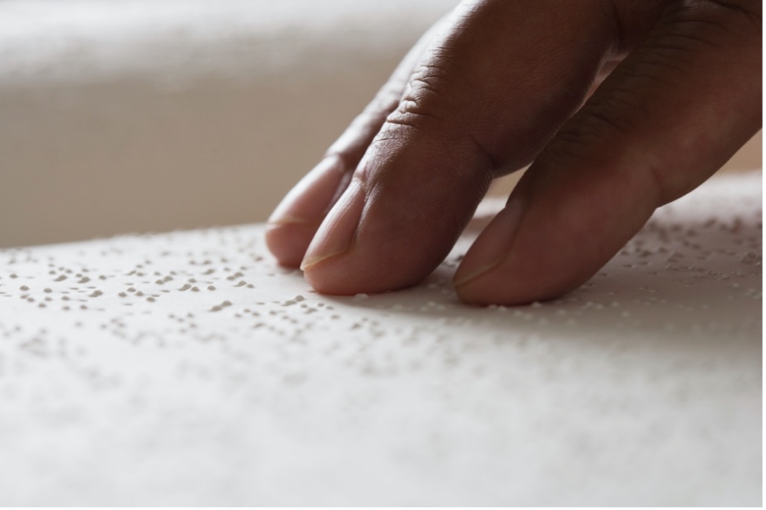 A hand scanning over a page with braille on it