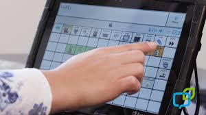 A child's hand hovers over a touch screen icon on a speech generating device