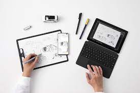 Hands are drawing a picture on a piece of paper using a smart pen, which displays it on a nearby tablet digitally.