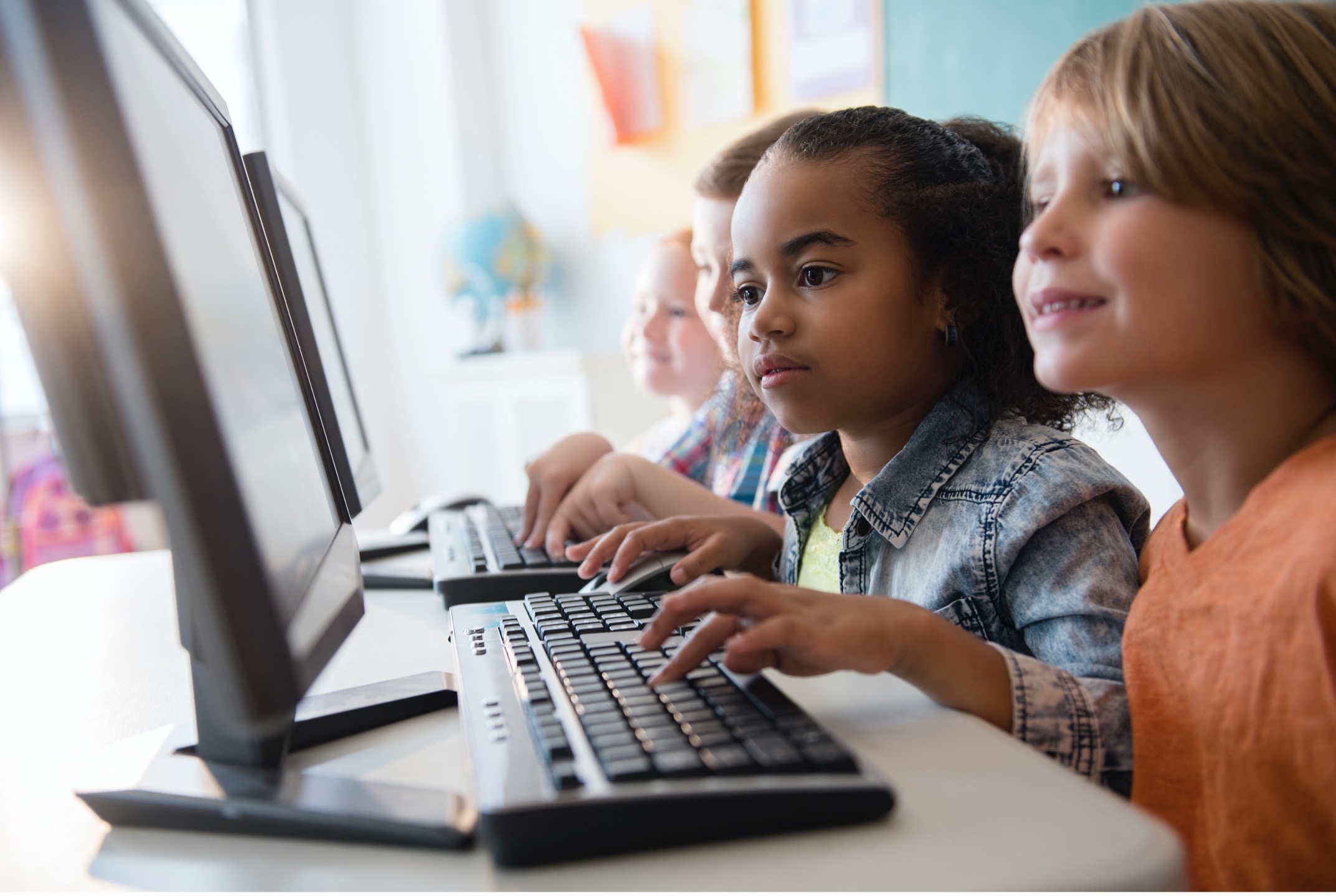 Children pressing buttons on keyboards to use computers