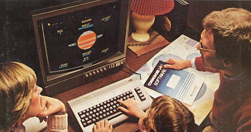 A person typing on a keyboard facing a computer screen that is sitting on a wooden desk.