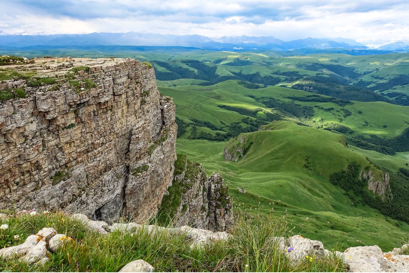 A picture of a plateau with rolling green hills underneath it