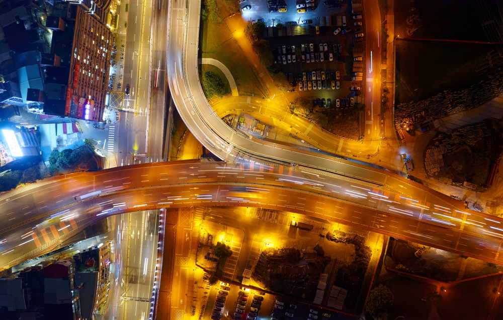 A picture of many lanes of traffic on a highway entrance at night lit up in red and white in both directions respectively